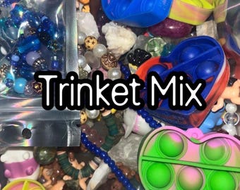 May include: A mix of trinkets including heart-shaped pop-it toys in pink, green, and blue, beads, and small figurines. The text "Trinket Mix" is displayed in a black font.