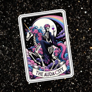May include: A tarot card with a black and white skeleton riding a unicorn. The card has a rainbow background and the text "THE AUDACITY" at the bottom.