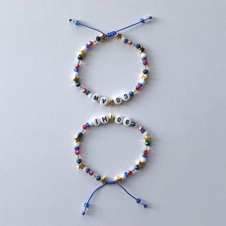 May include: Two adjustable bracelets featuring blue, red, white, and clear beads interspersed with small gold-coloured stars. One bracelet displays the letters MV and the numbers 03, while the other displays the letters IH and the numbers 06.