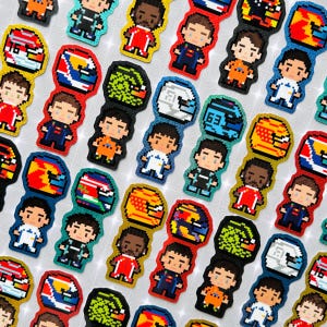May include: A selection of pixel art racing driver and helmet designs in various colours. The drivers are shown in different racing suits, and the helmets feature unique patterns and numbers. The overall theme is motorsports.