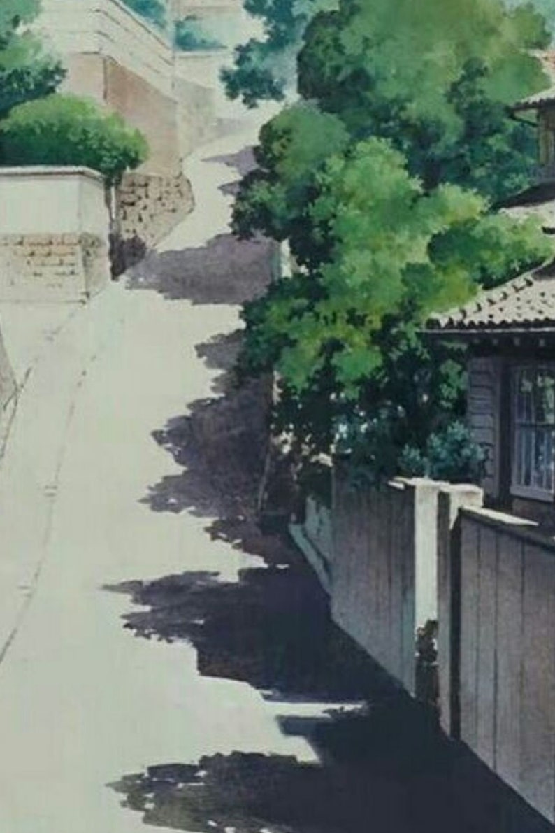 May include: A narrow, winding street in a Japanese neighborhood. The street is lined with traditional houses and lush green trees. The houses have white walls and brown roofs. The street is paved with gray concrete and has a slight incline.