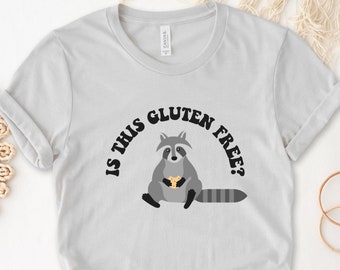 May include: A gray t-shirt with a raccoon holding a cookie and the text "Is this gluten free?" printed on it.