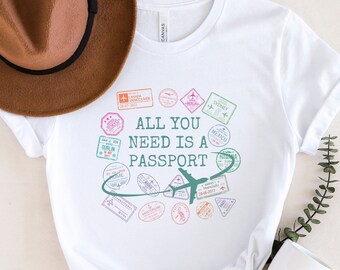 May include: White t-shirt with a graphic of a plane and passport stamps that says "All you need is a passport".