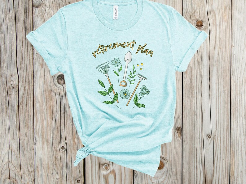 May include: A light blue t-shirt with the text "retirement plan" in gold lettering. The design features gardening tools, flowers, and leaves.