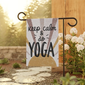 May include: A garden flag with a white background and a yellow sun with rays. The text "Keep calm & do YOGA" is written in black on the flag.