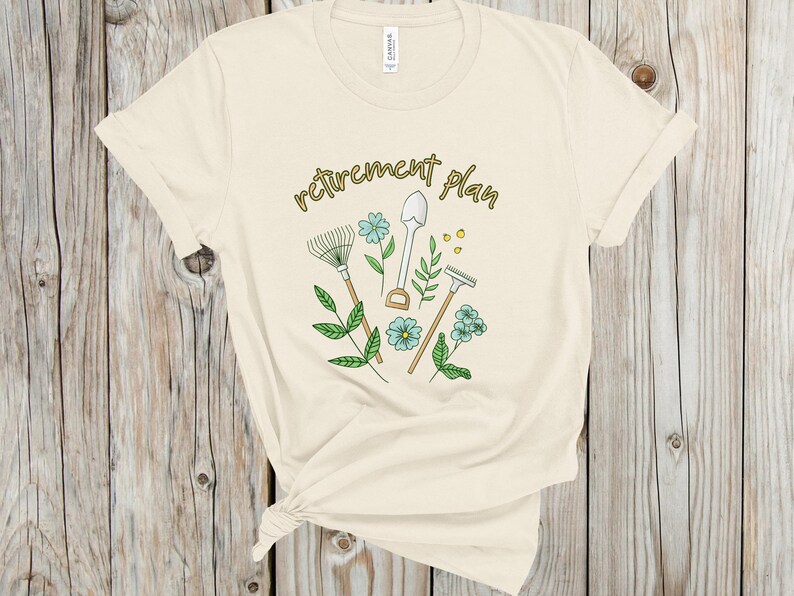 May include: A beige t-shirt with the text "retirement plan" in gold lettering. The design features gardening tools, including a rake, shovel, and trowel, with green leaves and blue flowers.