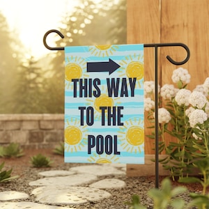 May include: A blue and yellow garden flag with a sun pattern and the text "This Way To The Pool" with a black arrow pointing to the right.