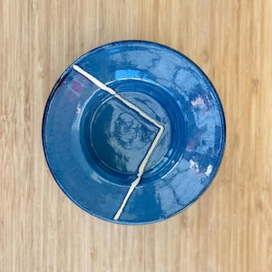 May include: A blue ceramic plate with a white geometric design. The plate has a slightly raised rim and a glossy finish.