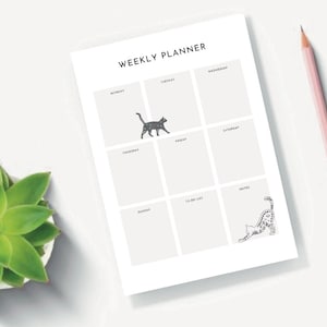 May include: A weekly planner with a black and white cat illustration. The planner has spaces for each day of the week, a to-do list, and notes.