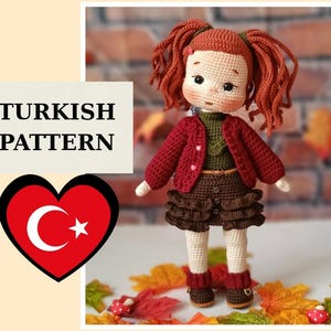 May include: A handmade crochet doll with red hair in pigtails, wearing a red jacket, brown skirt, and boots. The doll has a sweet expression. The image includes the text "TURKISH PATTERN" and a heart with the Turkish flag.