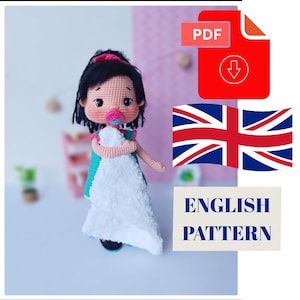 May include: A handmade crochet doll with black hair, a pink pacifier, and a white dress. The doll has a pink headband and is holding a white blanket. The image includes a PDF icon, a British flag, and the words "ENGLISH PATTERN".