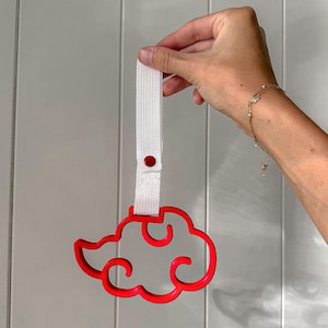 May include: A red plastic cloud-shaped handle with a white woven fabric strap attached by a small red snap button. The cloud design features a stylized, open-center silhouette with curved edges, suspended from the vertical white strap.
