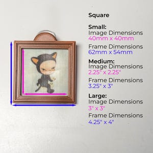 K&ouml;nnte beinhalten: Ein quadratisches, gerahmtes Kunstwerk mit einer Cartoonfigur in einem schwarzen Katzenkost&uuml;m. Der Rahmen hat eine warme braune Farbe. Die Bildabmessungen betragen 5,7 cm x 5,7 cm und die Rahmenabmessungen 8,3 cm x 7,6 cm. Der Text auf dem Bild lautet "Square".