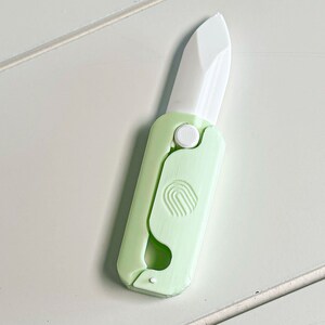 May include: A white ceramic mug with a colorful floral design. The mug features a handle and a wide opening. The flowers are in shades of pink, purple, and yellow. The mug is likely used for hot beverages.