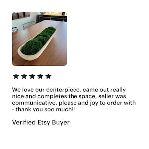 May include: A long, narrow, light-colored wooden dough bowl filled with vibrant green moss. The bowl has a smooth, curved interior and a natural wood grain finish, containing several rounded mounds of preserved moss arranged in a single row.