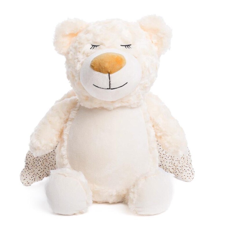 Op de afbeelding: Een cr&egrave;mekleurige pluche teddybeer met een lachend gezicht en gesloten ogen. De beer heeft een bruine neus en zwarte geborduurde details. De poten hebben een stippenpatroon. De beer zit rechtop.