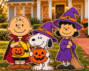 May include: A set of three Peanuts character yard decorations featuring Charlie Brown in a vampire cape, Snoopy in a purple witch hat, and Lucy in a purple witch costume holding a broom, each holding a carved orange jack-o'-lantern.