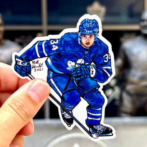 May include: A blue and white hockey player sticker with the number 34 on the jersey. The player is wearing a helmet and holding a hockey stick. The sticker is signed "Mike Knight: 2021".
