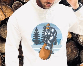May include: White hooded sweatshirt with a graphic of a yeti wearing goggles and snowboarding down a mountain. The graphic is in blue, brown, and white.