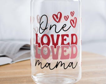 May include: A clear glass can with a red and pink design that says "One Loved Loved mama" with hearts around the text.