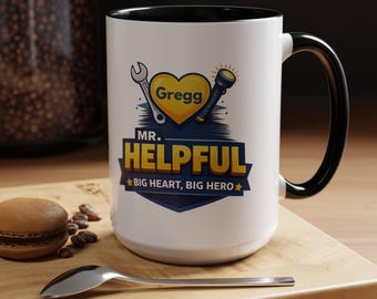 May include: White ceramic mug with a black interior and handle. The mug features the text "Mr. Helpful" with a wrench and flashlight graphic, and the name "Gregg" inside a yellow heart. The phrase "Big Heart, Big Hero" is also included.
