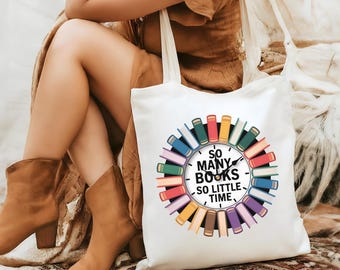 May include: White tote bag featuring a colorful circular design of books surrounding a clock face. The text on the bag reads "So Many Books, So Little Time."