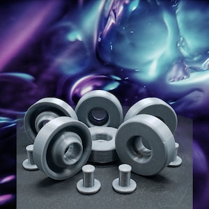 May include: A set of eight gray plastic furniture feet with a round top and a small stem. The feet are arranged in a circle on a black surface.