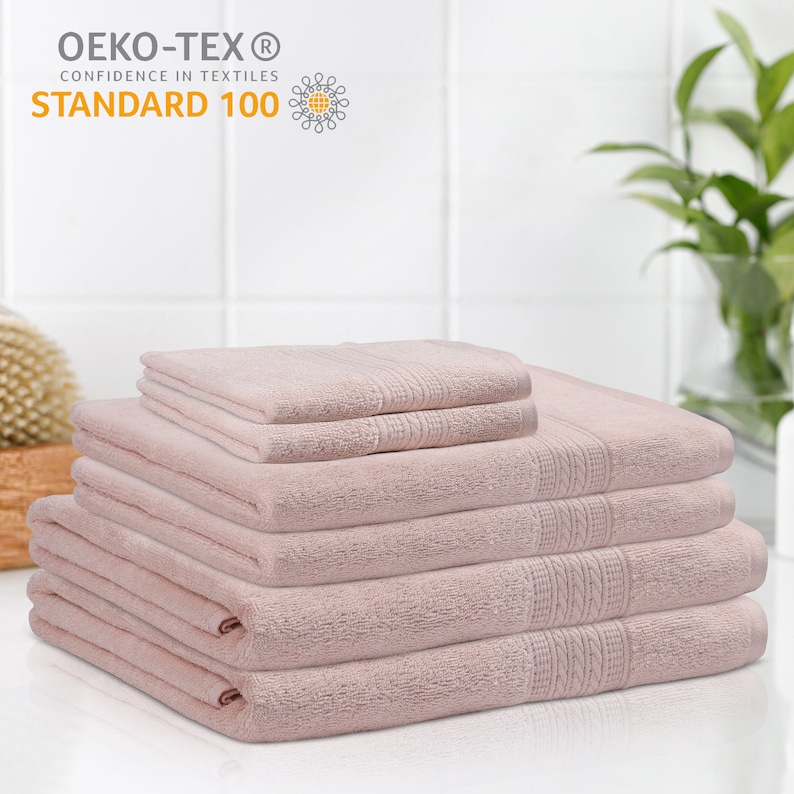 May include: A stack of six pink bath towels. The towels are made of soft, absorbent cotton and are Oeko-Tex Standard 100 certified.