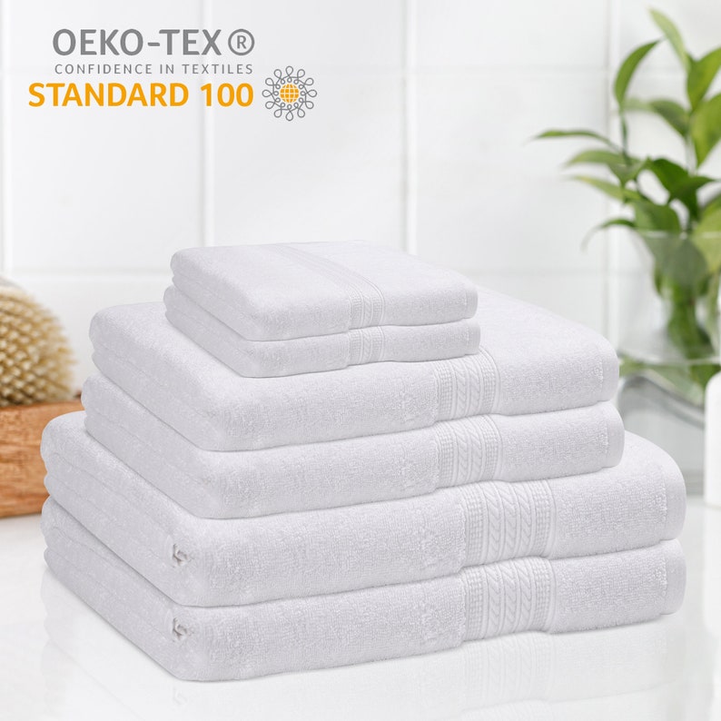 May include: A stack of six white bath towels. The towels are folded and arranged in a pyramid shape. The towels are made of soft, absorbent cotton. The towels are certified Oeko-Tex Standard 100, which means they are free of harmful chemicals.