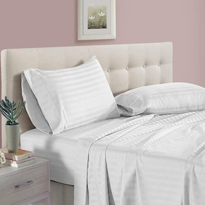 May include: White striped bed sheet set with two white striped pillowcases. The bed sheet set is on a bed with a light beige headboard.