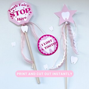 May include: Two pink tooth fairy wands with white tooth designs. One wand has a pink stop sign with the text "Tooth Fairy Stop Here" and the other wand has a pink circle with the text "I Lost A Tooth!"