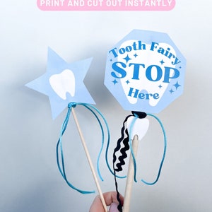 May include: Two tooth fairy wands, one shaped like a star and the other a stop sign. Both are blue with white tooth outlines and the stop sign says "Tooth Fairy Stop Here".