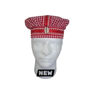 May include: A red and white gingham patterned hat featuring a structured band with a horizontal red ribbon, a white wavy trim, and a single cowrie shell centered on the front. The hat is displayed on a white mannequin head with a black NEW label.