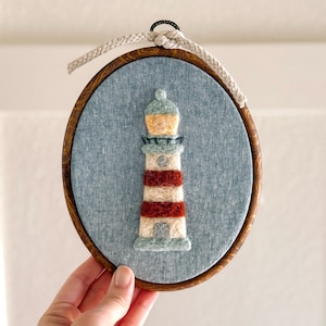 May include: A white ceramic mug with a black handle and the text "But First, Coffee" in a bold, black font. The mug is set against a blurred background, suggesting a cozy setting.