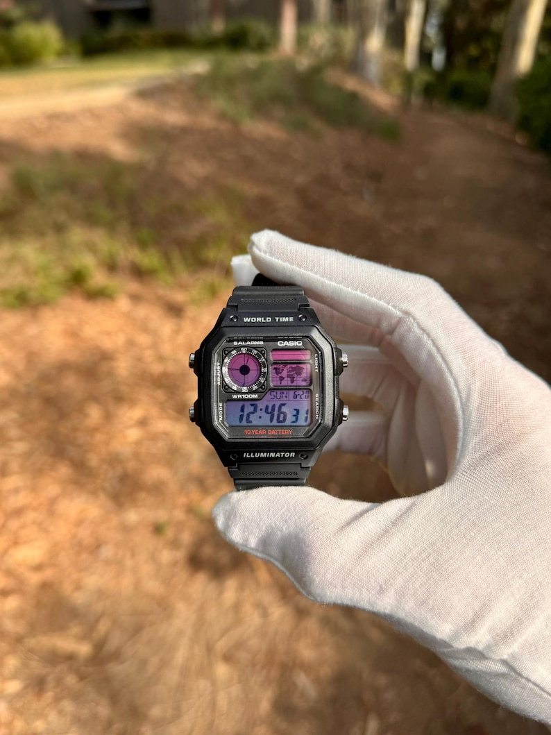 May include: Black Casio digital watch with a black strap. The watch face displays the time, date, and other features. The watch has a world time function and an illuminator.