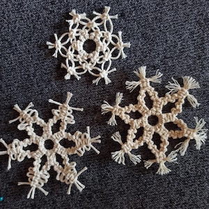 May include: Three white crocheted snowflakes with fringe details.