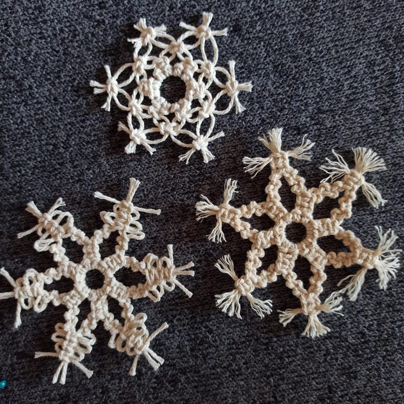 May include: Three white crocheted snowflakes with fringe details.