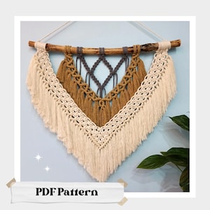 May include: A macrame wall hanging with a wooden dowel at the top. The macrame is made with white, beige, and gray yarn and has a fringe at the bottom. The wall hanging is in a V-shape and has a geometric pattern. "PDF Pattern" is written at the bottom of the image.
