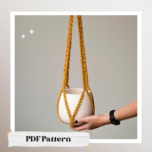 Puede incluir: Colgador de plantas de macramé amarillo mostaza que sostiene una maceta de cerámica blanca con estrías verticales. El colgador de plantas está suspendido de dos cuerdas trenzadas. El texto "PDF Pattern" está en la parte inferior de la imagen.