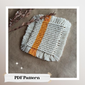 May include: A white crocheted coaster with a yellow stripe down the center. The coaster has a fringe border.