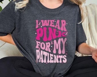 May include: A dark grey t-shirt with the text "I wear pink for my patients" in pink lettering with pink ribbon accents.