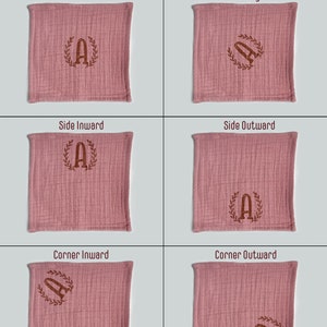 May include: Six pink fabric squares with different embroidery placement options. The embroidery is a brown letter "A" inside a wreath. The options are: Center Horizontal, Center Diagonal, Side Inward, Side Outward, Corner Inward, Corner Outward.