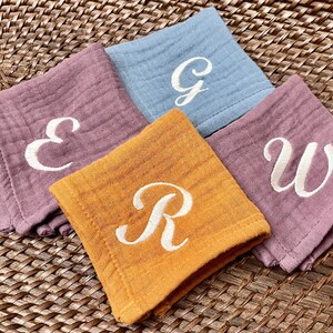 May include: Four fabric squares with embroidered letters. The squares are in shades of pink, blue, yellow, and orange. The letters are E, G, W, and R.