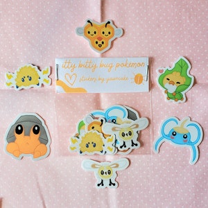 May include: A set of 10 small, colorful, cartoon-style Pokemon stickers. The stickers feature various Pokemon characters, including a bee, a crab, a bug, and a butterfly. The stickers are labeled "itty bitty bug pokemon stickers by yawncake".
