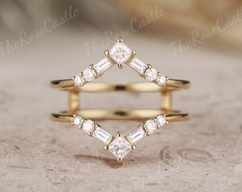 May include: A gold ring with a double band design. The top band features a square-shaped diamond in the center with smaller diamonds on either side. The bottom band has a similar design with a smaller square-shaped diamond in the center.