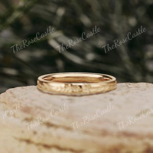K&ouml;nnte beinhalten: Ein goldfarbener Ring mit floralem Muster. Der Ring liegt auf einer Steinoberfl&auml;che. Der Text "The Rose Castle" ist im Hintergrund sichtbar.