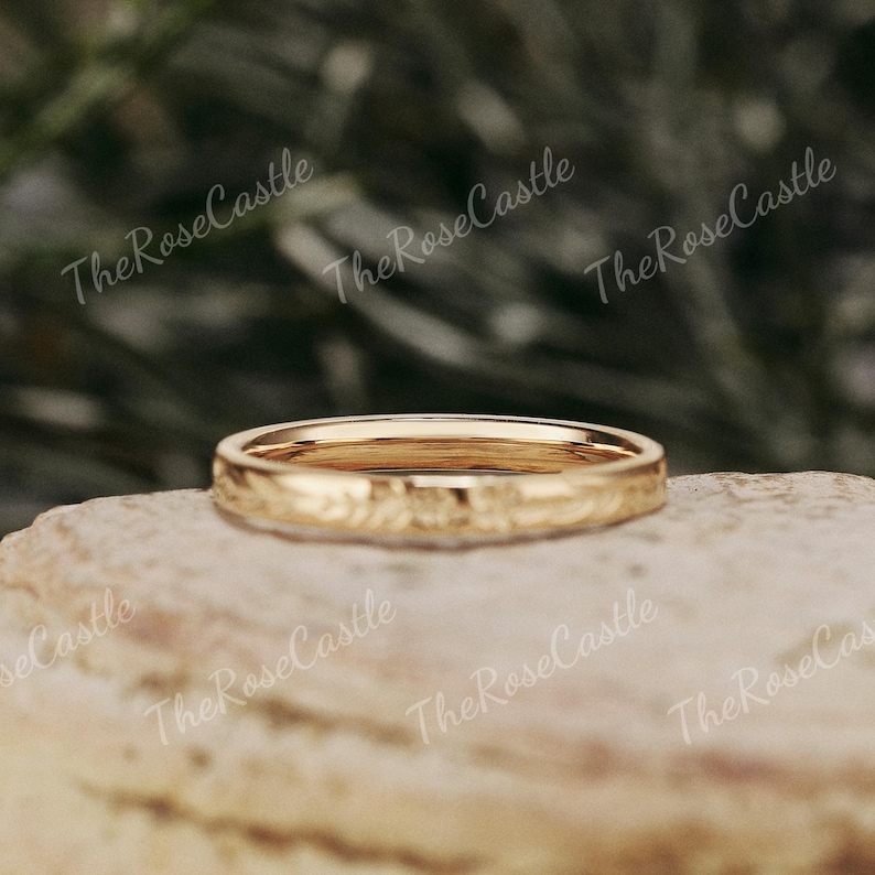 K&ouml;nnte beinhalten: Ein goldfarbener Ring mit floralem Muster. Der Ring liegt auf einer Steinoberfl&auml;che. Der Text "The Rose Castle" ist im Hintergrund sichtbar.