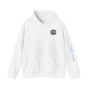 May include: White hoodie with a front pocket and a drawstring hood. A circular emblem is on the upper left chest, and the words "REEL TIDES" are printed in blue on the right sleeve. The hoodie is made of a soft material.