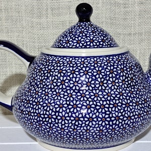 May include: A blue and white ceramic teapot with a floral pattern. The teapot has a lid and a spout.