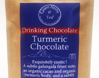 May include: A brown paper pouch with a blue label that reads "Giant Herbs & Tea® Thinking big in small batches Drinking Chocolate Turmeric Chocolate Exquisitely exotic! A subtle galangala front note, an organic cacao and organic turmeric body, and a subtly sweet finish. Net Wt: 2 oz. (56 g.)"